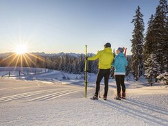 Two skiers enjoying the sunset in a snowy mountain landscape