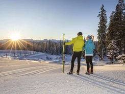 Two skiers enjoying the sunset in a snowy mountain landscape