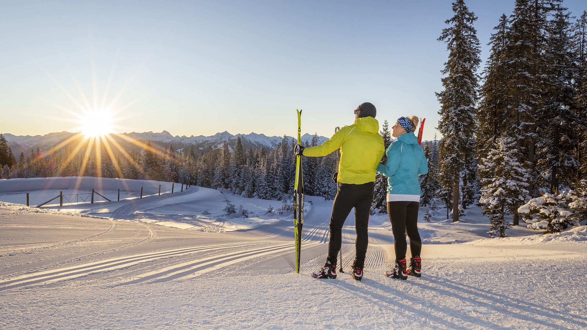 Zwei Skifahrer genießen den Sonnenuntergang in verschneiter Berglandschaft
