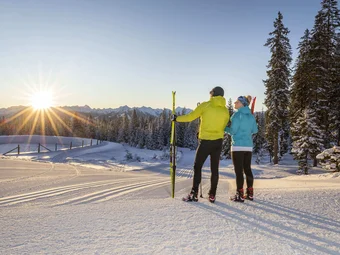 Two skiers enjoying the sunset in a snowy mountain landscape