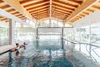 Collective enquiries Two people relaxing in indoor pool with wooden ceiling and large windows