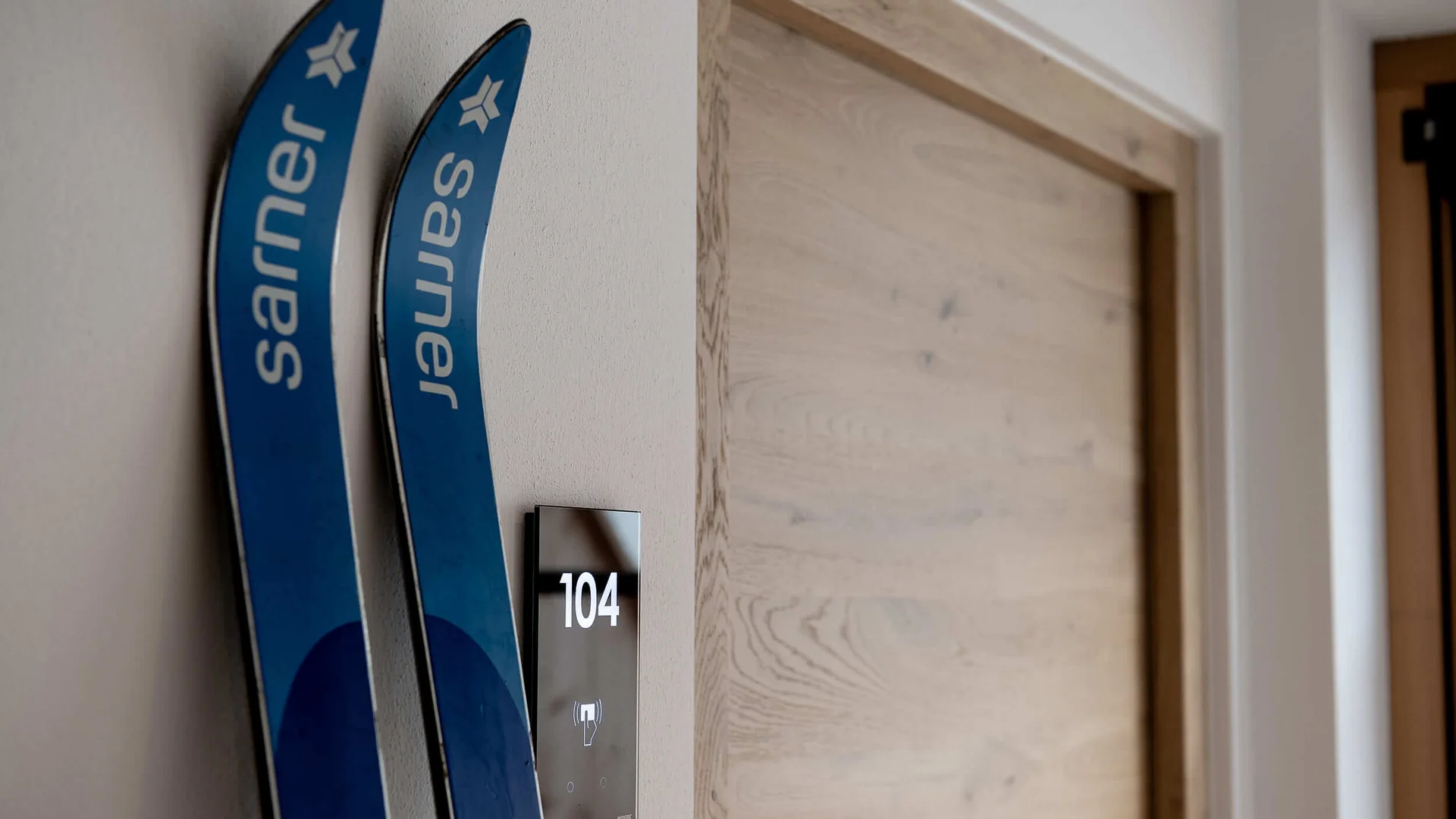 Blaue Karvingski lehnen an einer weißen Wand neben Tür 104