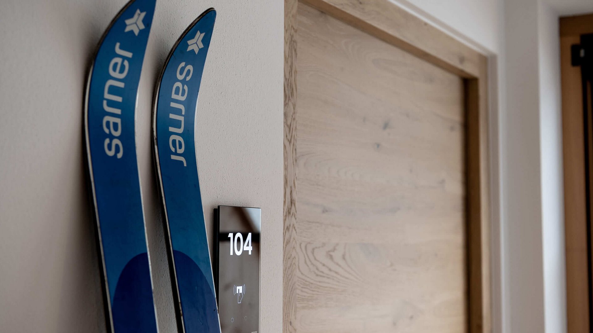 Blaue Karvingski lehnen an einer weißen Wand neben Tür 104
