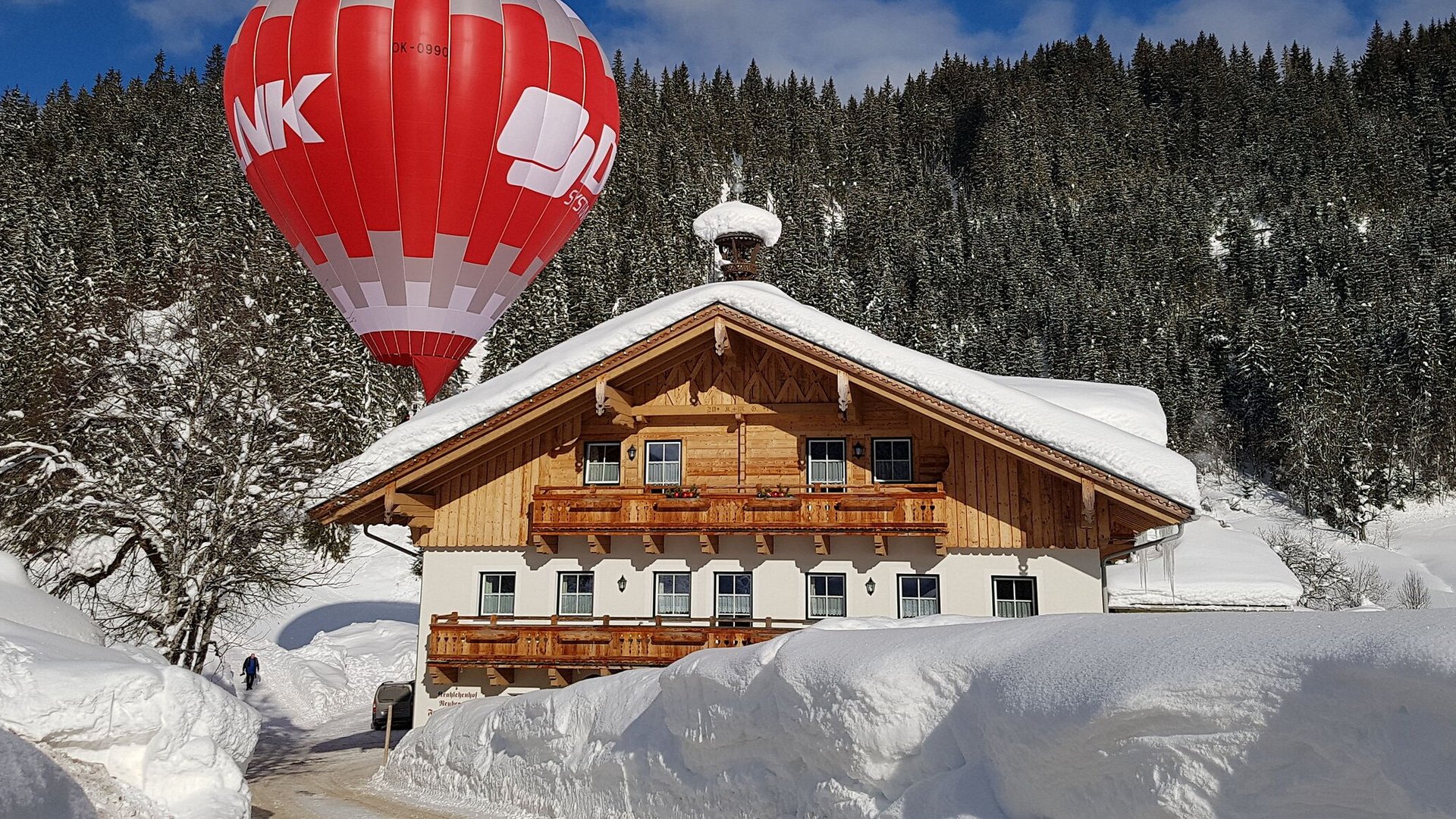 Hot air balloon above a snow-covered house in winter landscape