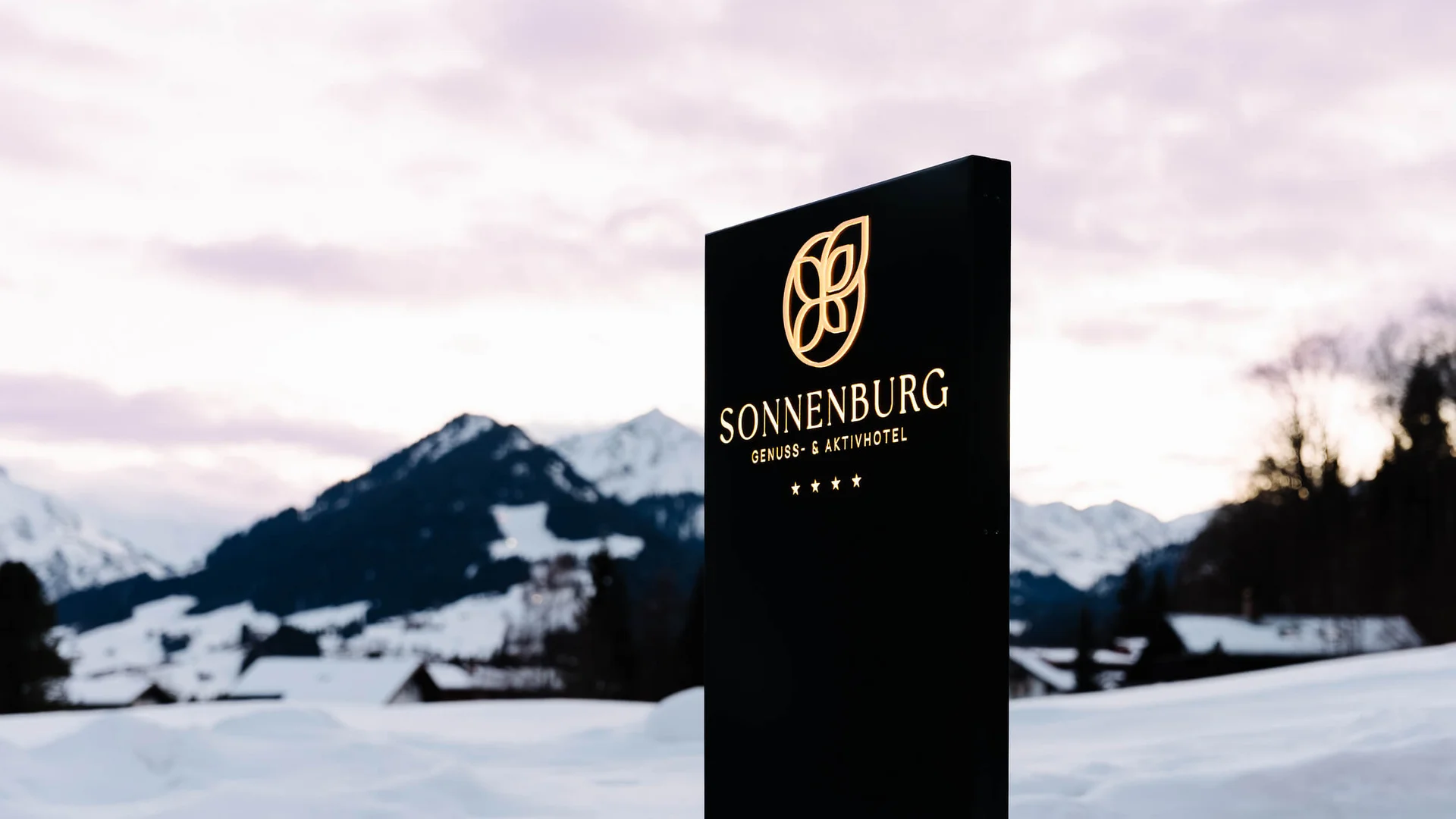 Genuss- und Aktivhotel Sonnenburg **** © Elisa Moosbrugger Schwarzes Sonnenburg-Hotelschild vor verschneiter Berglandschaft