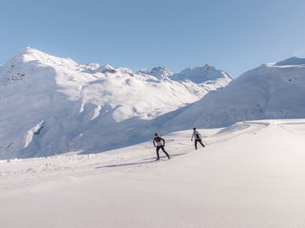 Paznaun - Ischgl/Galtür © TVB Paznaun-Ischgl Zwei Langläufer auf verschneiter Berglandschaft bei klarem Himmel