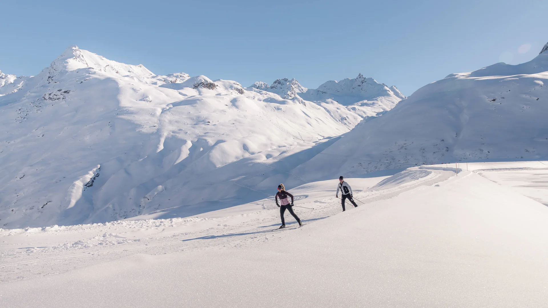 Loipen & Loipenbericht © TVB Paznaun-Ischgl Zwei Langläufer auf verschneiter Berglandschaft bei klarem Himmel