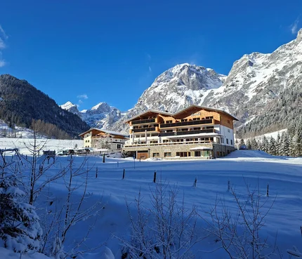 Hotel in verschneiter Berglandschaft unter klarem blauem Himmel