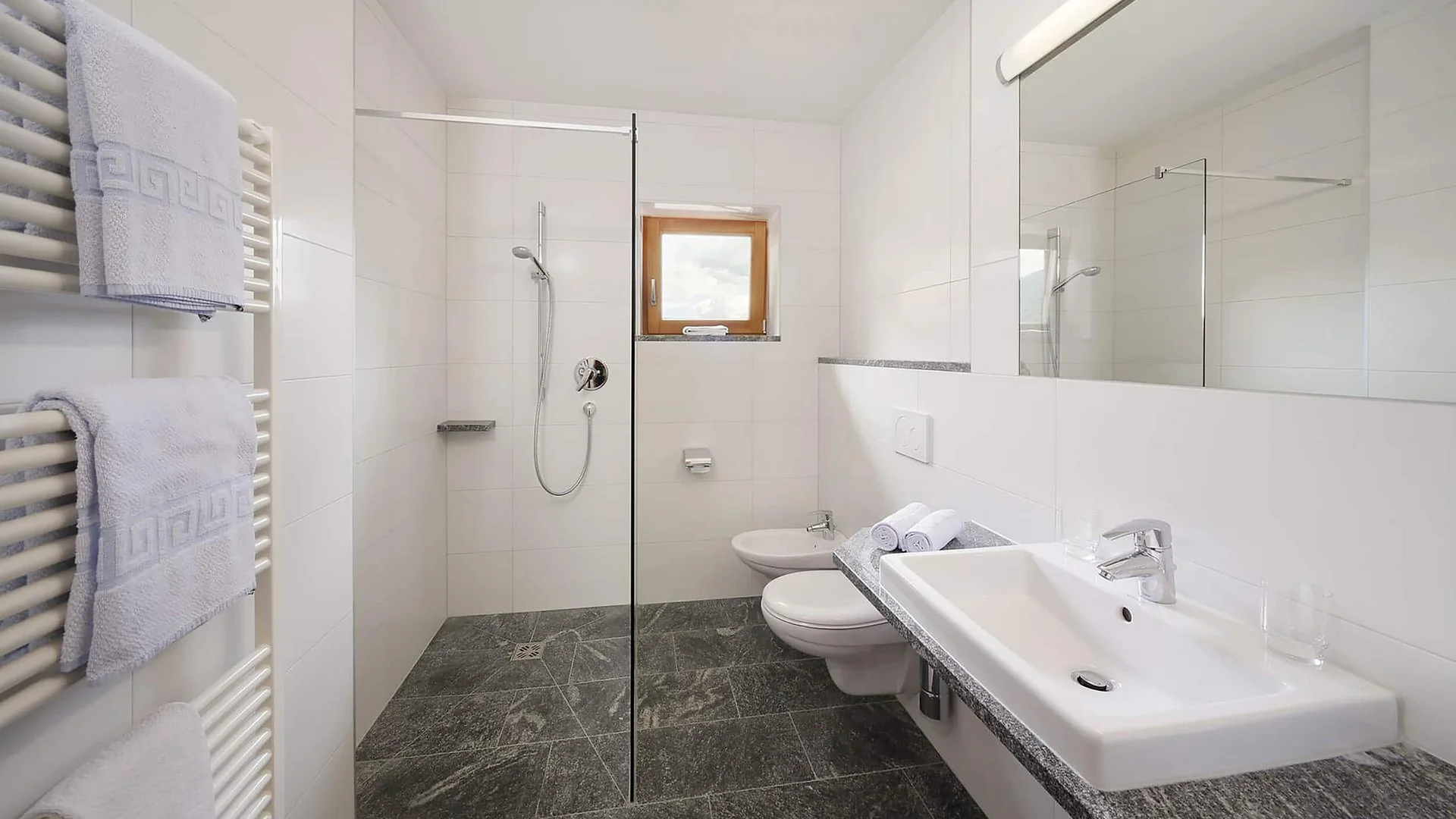 Helles Badezimmer mit Dusche, Waschbecken, WC und Handtuchheizkörper