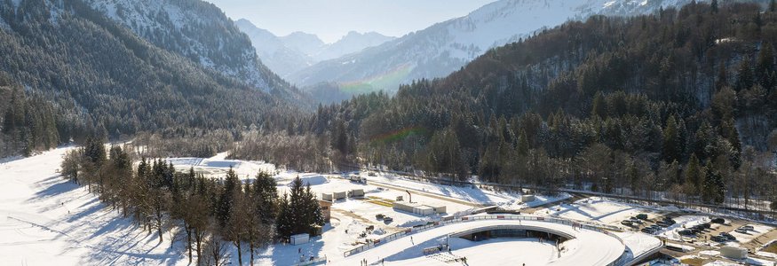 Unterwegs im Nordic Zentrum Oberstdorf © Tourismus Oberstdorf - Eren Karaman Verschneite Winterlandschaft mit Skifahrern und sonnigem Himmel in den Bergen