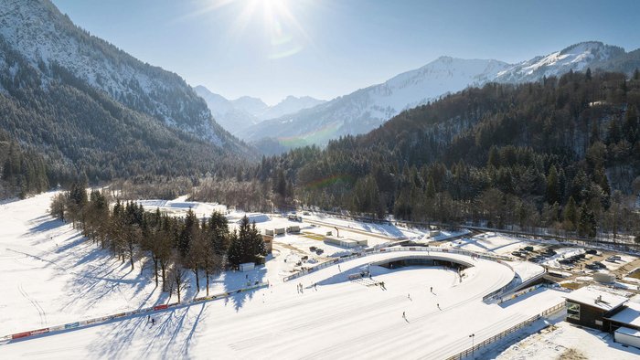 Hobby Biathlon © Tourismus Oberstdorf - Eren Karaman Verschneite Winterlandschaft mit Skifahrern und sonnigem Himmel in den Bergen