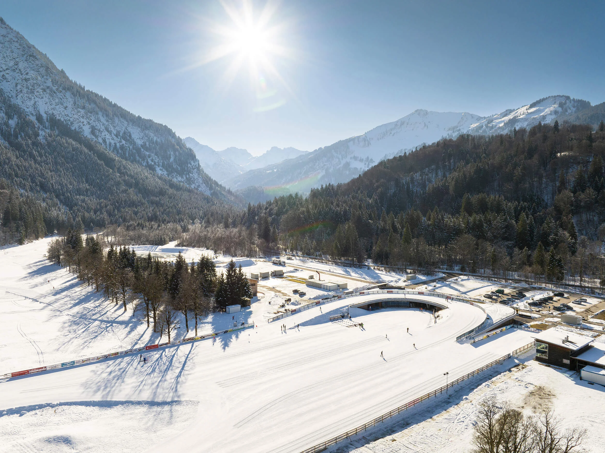 Verschneite Winterlandschaft mit Skifahrern und sonnigem Himmel in den Bergen