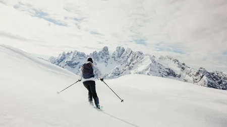 Skier skiing in snowy mountains with mountain range in the background