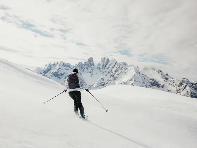 Skier skiing in snowy mountains with mountain range in the background
