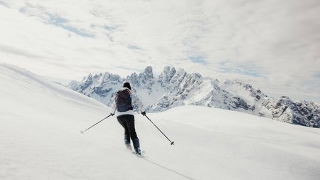 Skifahrer fährt im verschneiten Gebirge mit Bergen im Hintergrund