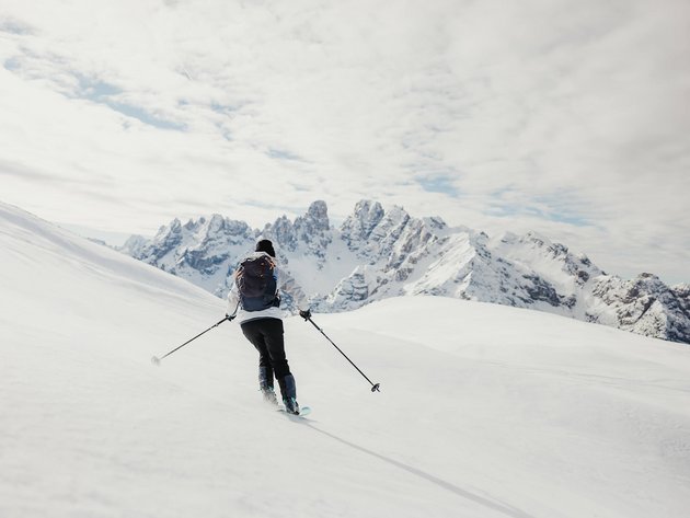 Skifahrer fährt im verschneiten Gebirge mit Bergen im Hintergrund