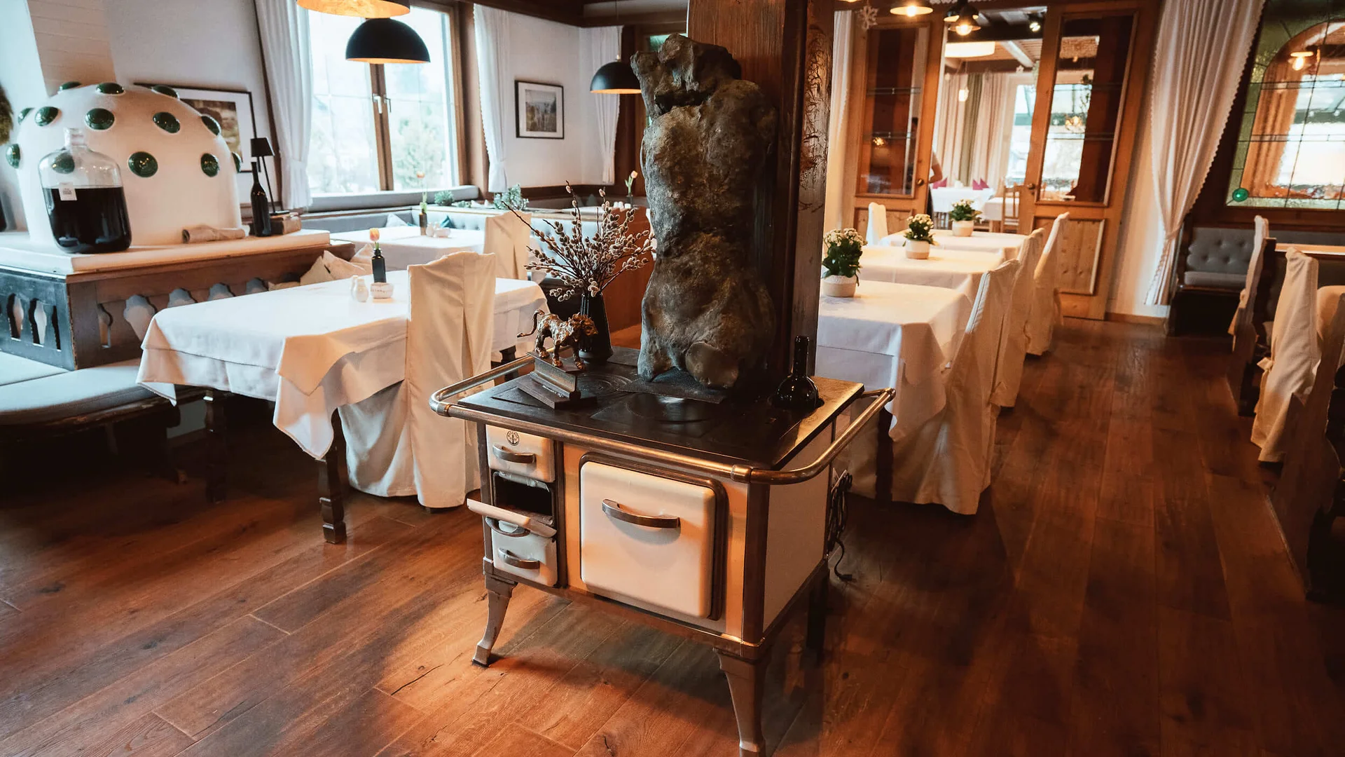 Hotel Kogler **** © Armin Ribis Restaurant mit gedeckten Tischen und antikem Herd mit Skulptur