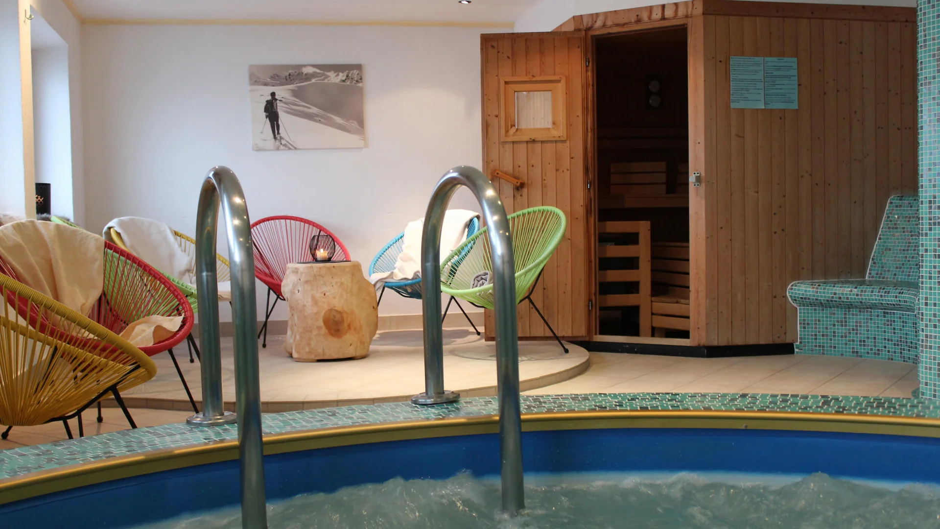 Whirlpool mit bunten Stühlen und Sauna in einem Wellnessraum