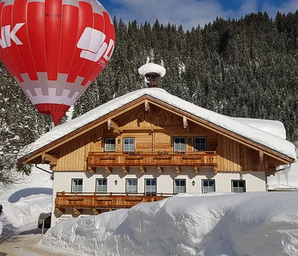 Hot air balloon above a snow-covered house in winter landscape