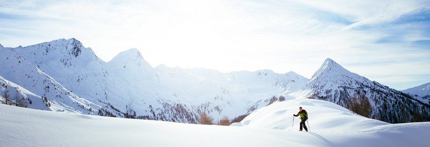 Skifahrer wandert auf schneebedecktem Berg im Sonnenlicht