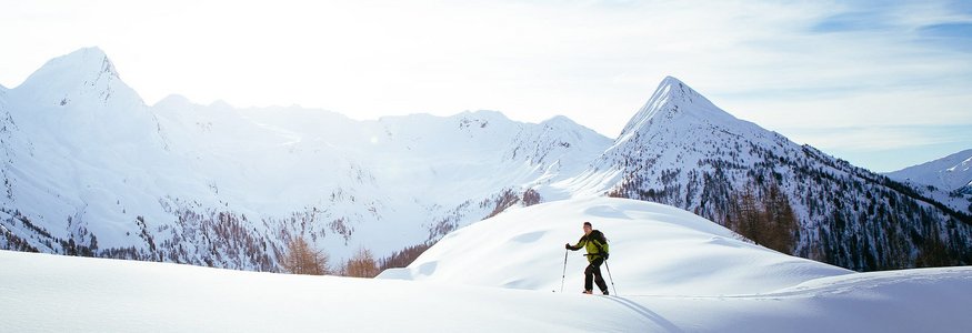 Skifahrer wandert auf schneebedecktem Berg im Sonnenlicht