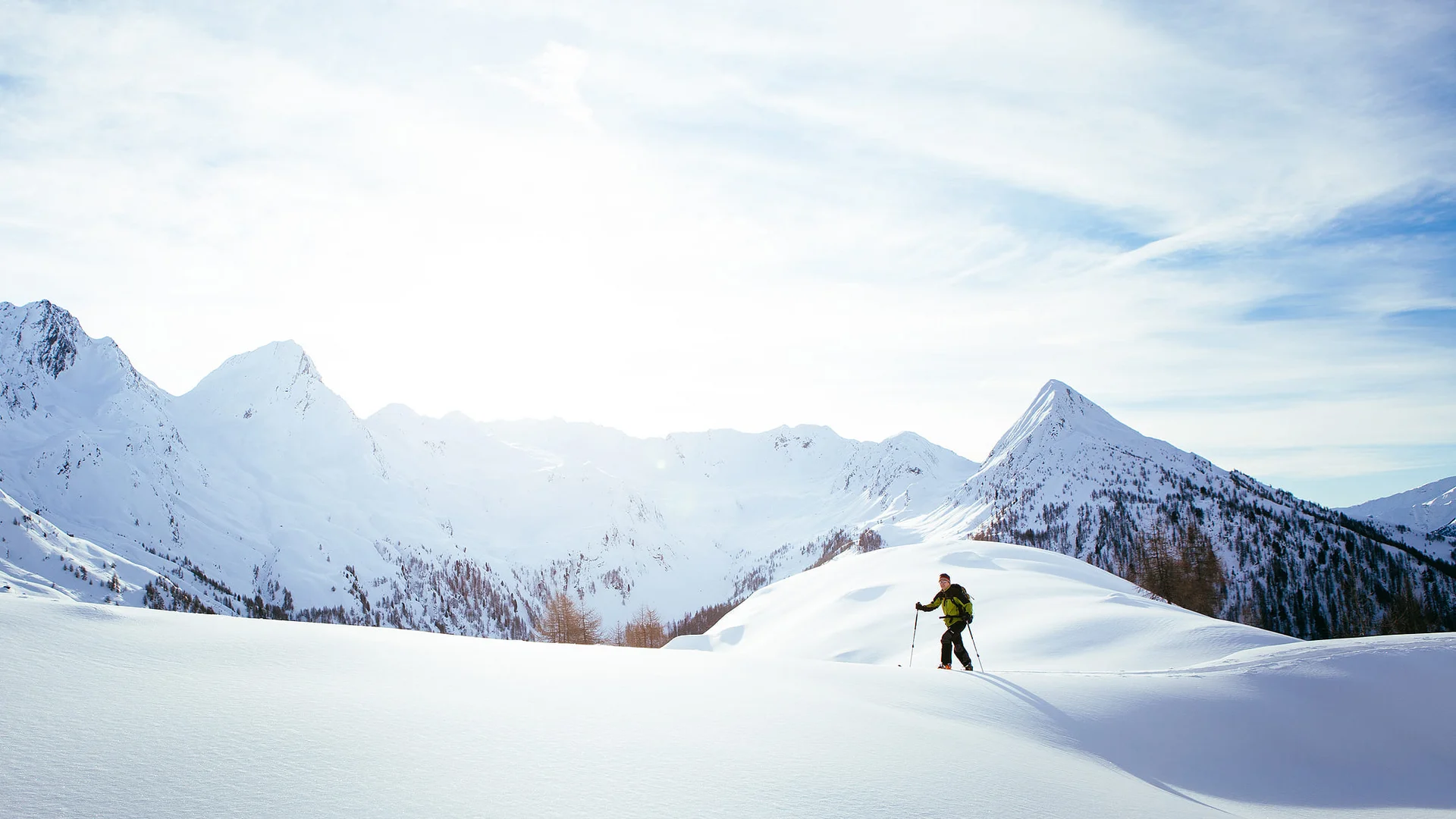 Skifahrer wandert auf schneebedecktem Berg im Sonnenlicht