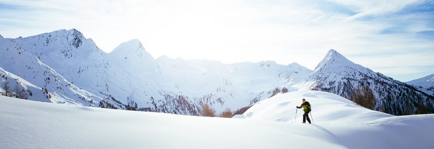 Skifahrer wandert auf schneebedecktem Berg im Sonnenlicht