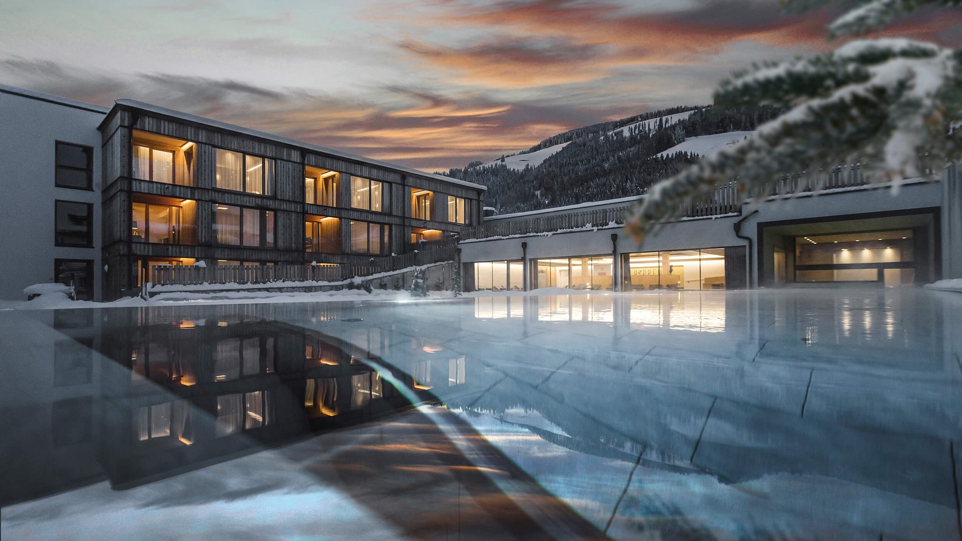 Modernes Hotel mit beleuchteten Fenstern bei Sonnenuntergang und Pool im Vordergrund