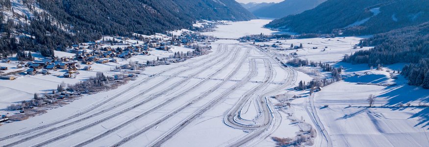 Verschneite alpine Landschaft mit Langlaufspuren und Bergen im Hintergrund