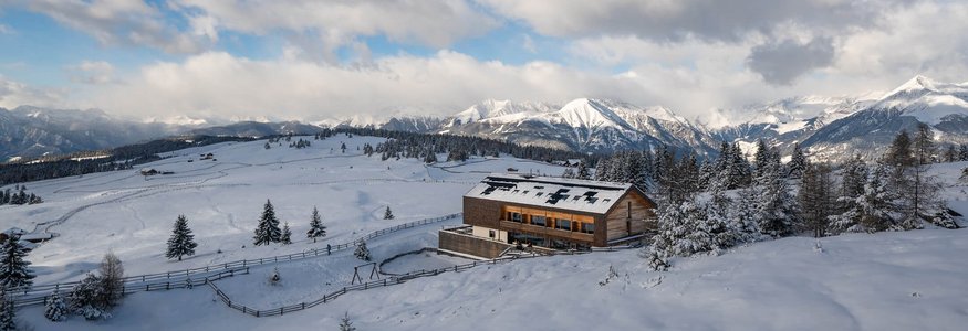 Holzhaus in verschneiter Berglandschaft mit bewölktem Himmel