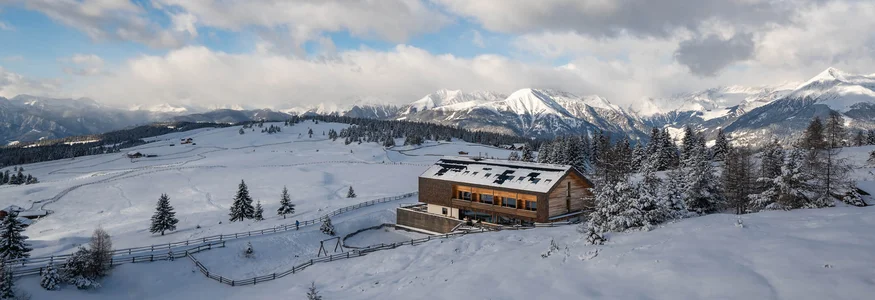 Alm-Hotel Starkenfeld Hütte ** © Jonas Eisenstecken Holzhaus in verschneiter Berglandschaft mit bewölktem Himmel