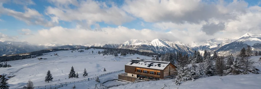 Gitschberg-Jochtal © Jonas Eisenstecken Holzhaus in verschneiter Berglandschaft mit bewölktem Himmel