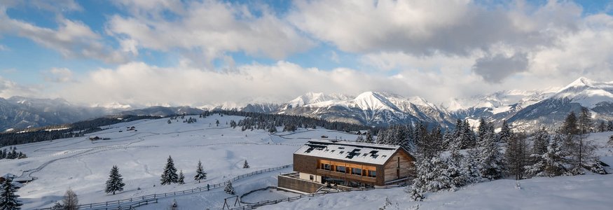 Holzhaus in verschneiter Berglandschaft mit bewölktem Himmel
