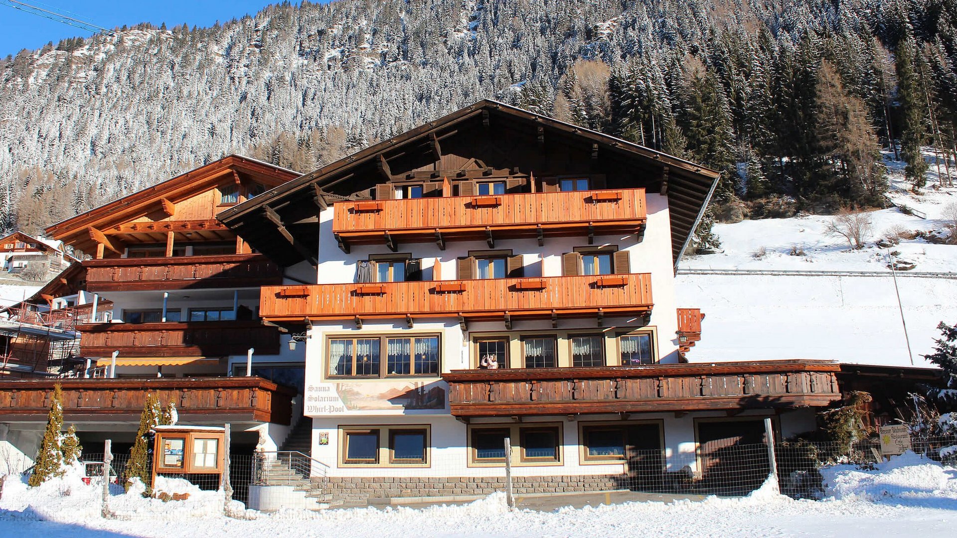 Alpenhaus mit verschneiten Bäumen im Hintergrund unter blauem Himmel