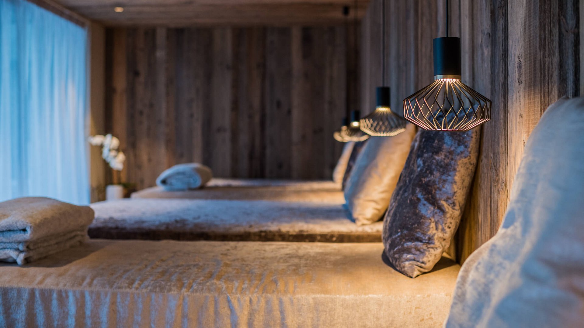 Entspannungsraum mit gepolsterten Liegen und modernem Wandlicht