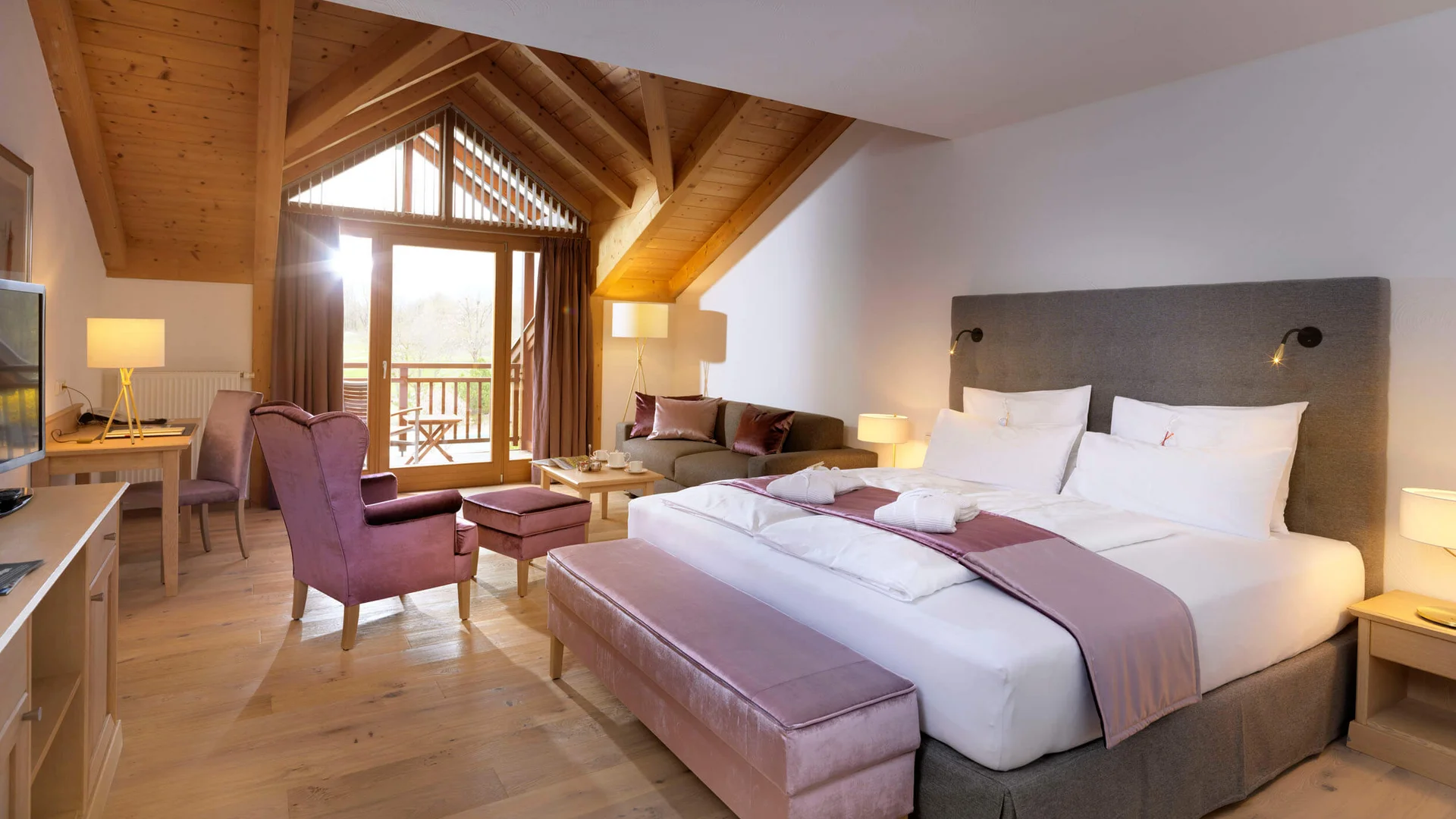 Gemütliches Hotelzimmer mit Holzbalkendecke, Balkon und modernen Möbeln