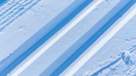 Schneesicher langlaufen: Wo Snowfarming in Österreich frühen Saisonstart möglich macht
© Martin Lugger Schneespuren im frischen, glatten Schnee unter Sonnenlicht