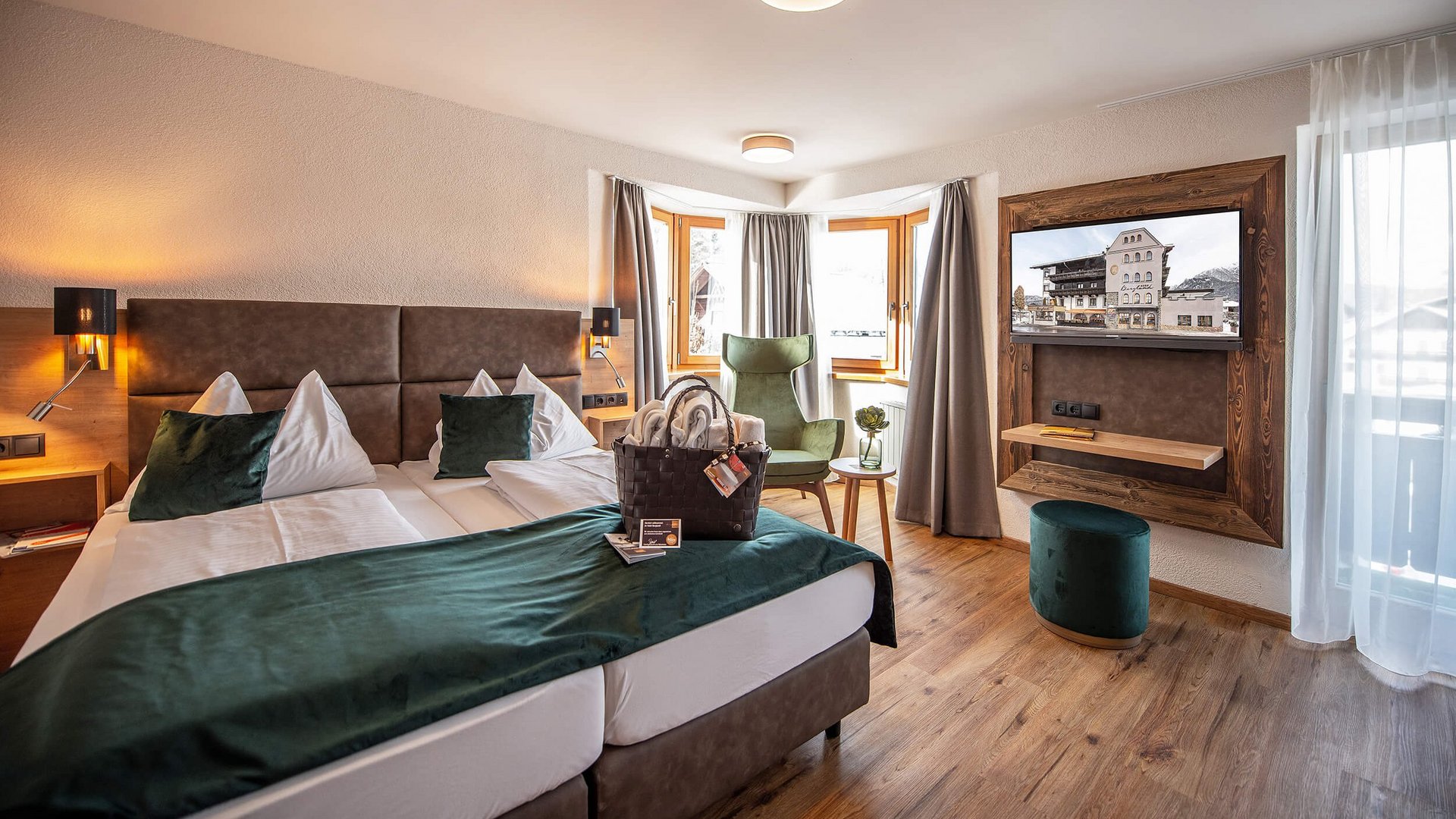 Cozy hotel room with two beds, armchair, and TV near large windows