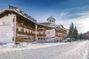 Schneebedecktes Alpenhotel mit blauem Himmel und verschneiter Straße