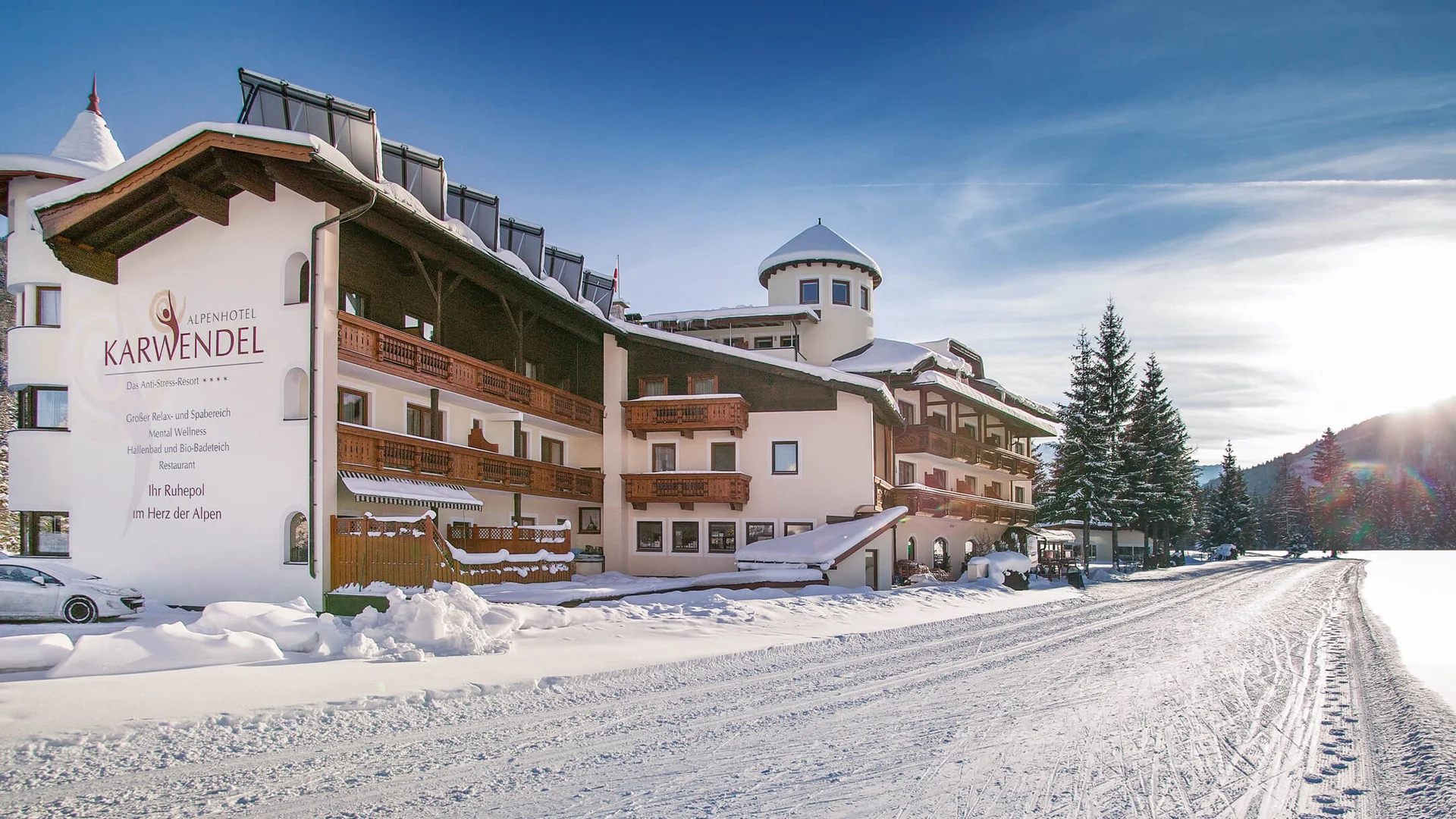 Alpenhotel Karwendel **** © Hotel Karwendel Bernhard Rödlach BetriebsGmbH Schneebedecktes Alpenhotel mit blauem Himmel und verschneiter Straße