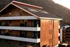 Modernes Holzhaus vor schneebedeckten Bergen im Sonnenlicht