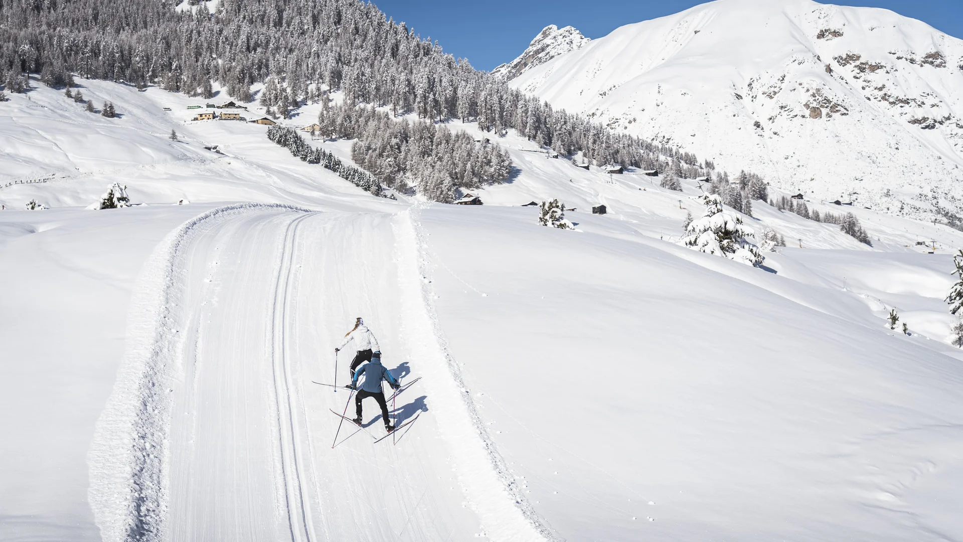 Two cross-country skiers on a snowy mountain trail