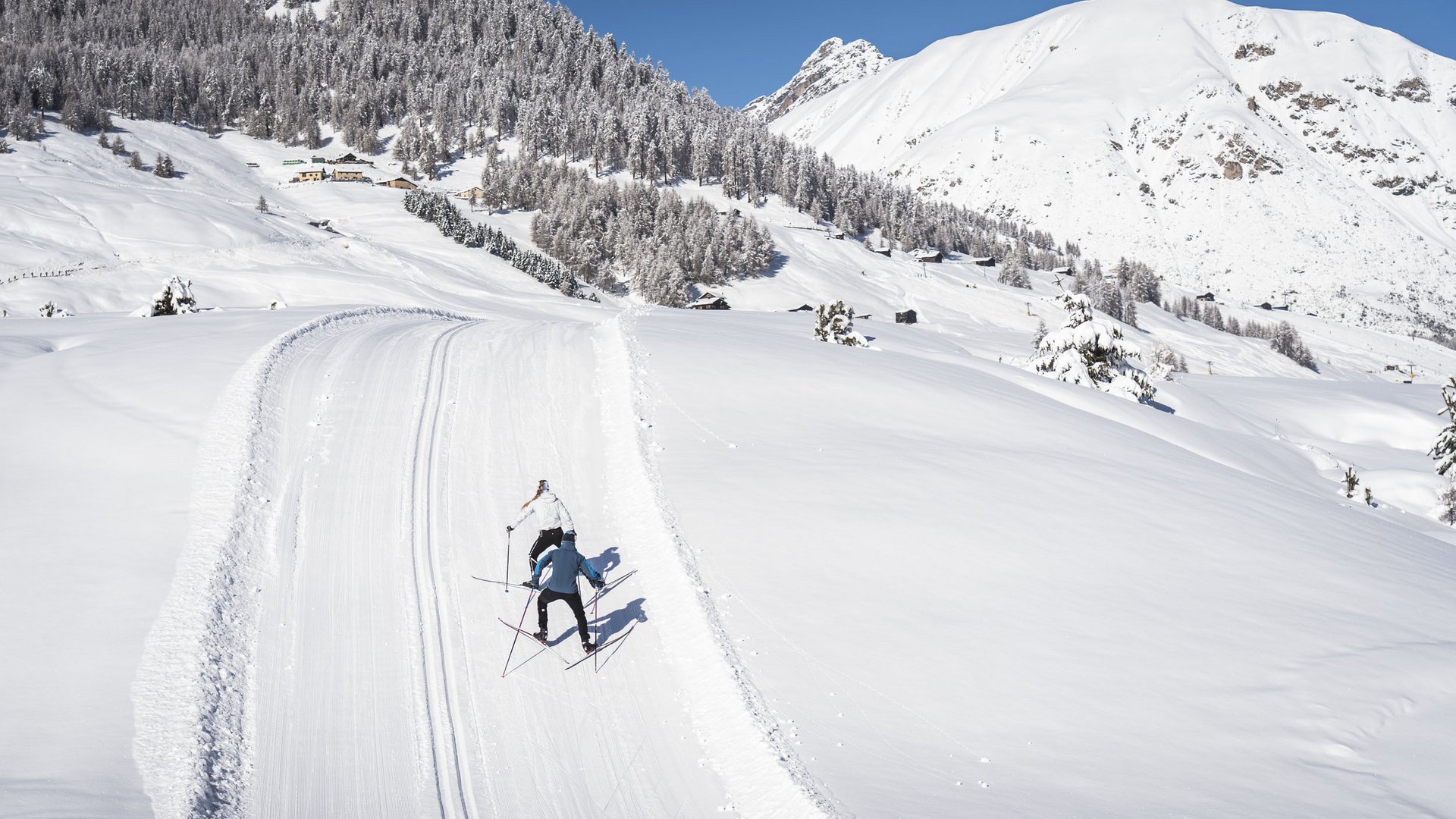 Zwei Skilangläufer auf einer verschneiten Strecke in den Bergen