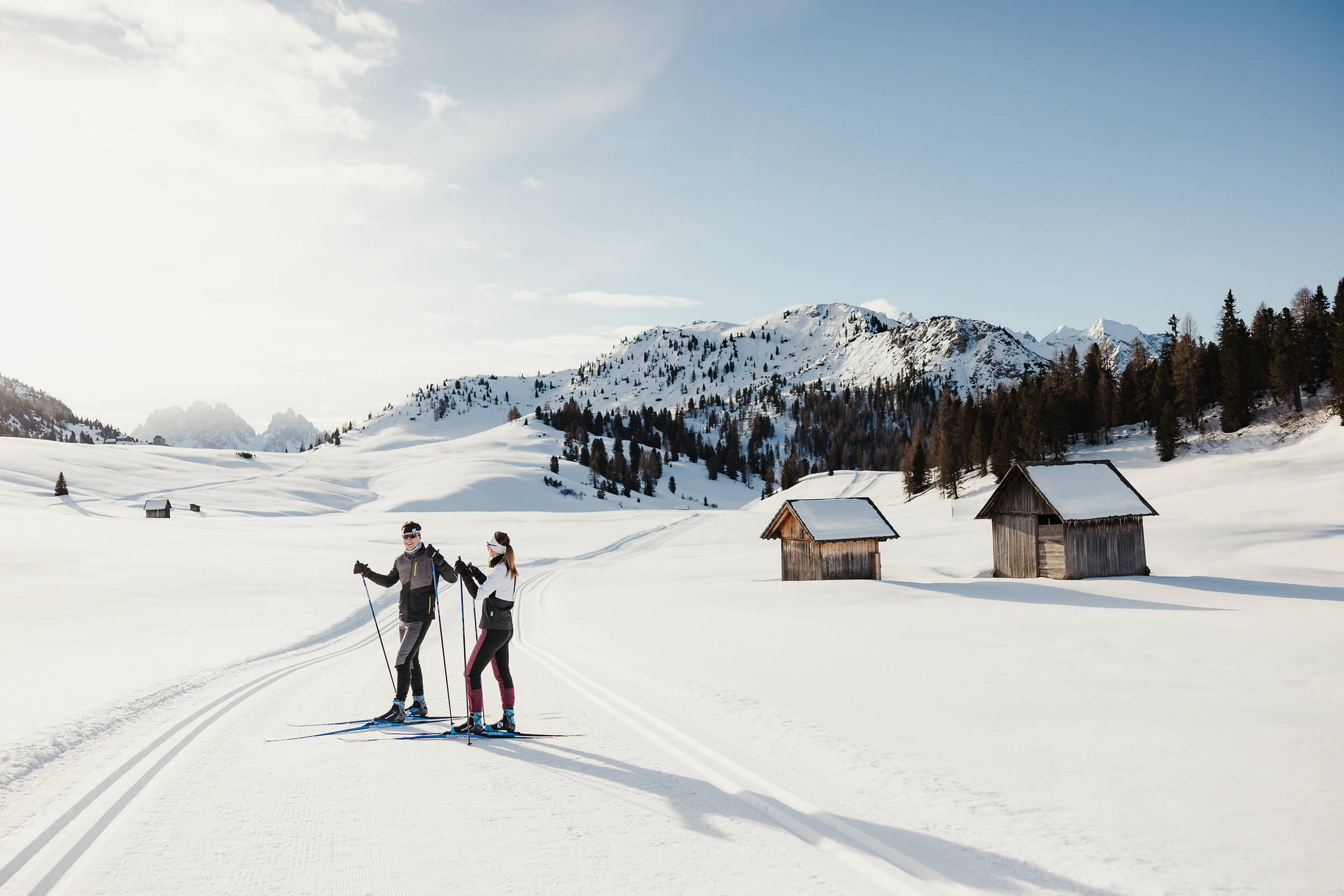 Cross Country Ski Holidays © Alex Moling Two cross-country skiers on snowy trail near cabins and mountains