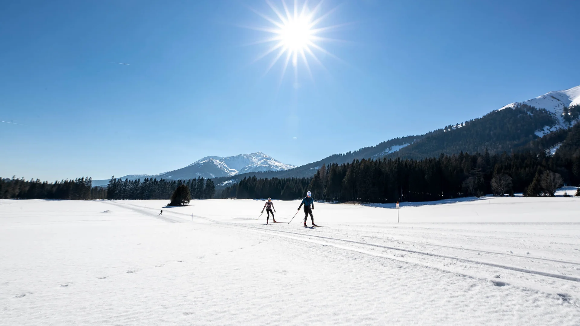 Langlauf Urlaub im Murtal © Tom Lamm Zwei Langläufer auf verschneiter Landschaft bei strahlendem Sonnenschein
