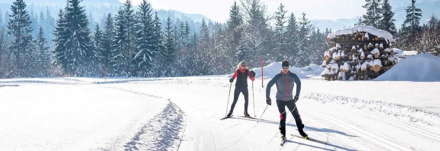 Die Kaiserwinklloipe © Tourismusverband Kaiserwinkl Zwei Langläufer auf schneebedeckter Loipe vor verschneiten Bergen