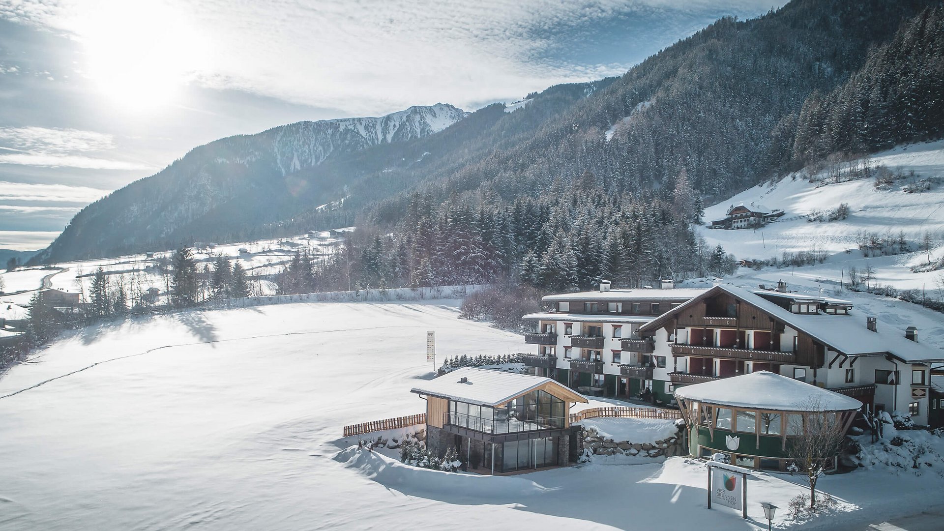 Winterlandschaft mit verschneitem Hotel und Bergen im Hintergrund