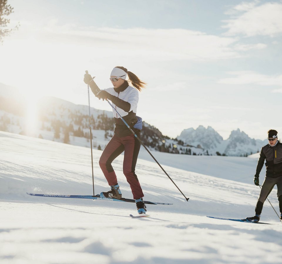 Top 5 für die Langlauf-Bucketlist © Alex Moling Zwei Personen Langlauf im Schnee mit Bergen im Hintergrund