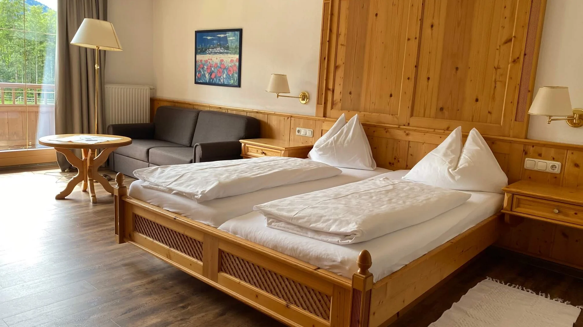 Gemütliches Hotelzimmer mit Doppelbett, Sofa und Holzmöbeln