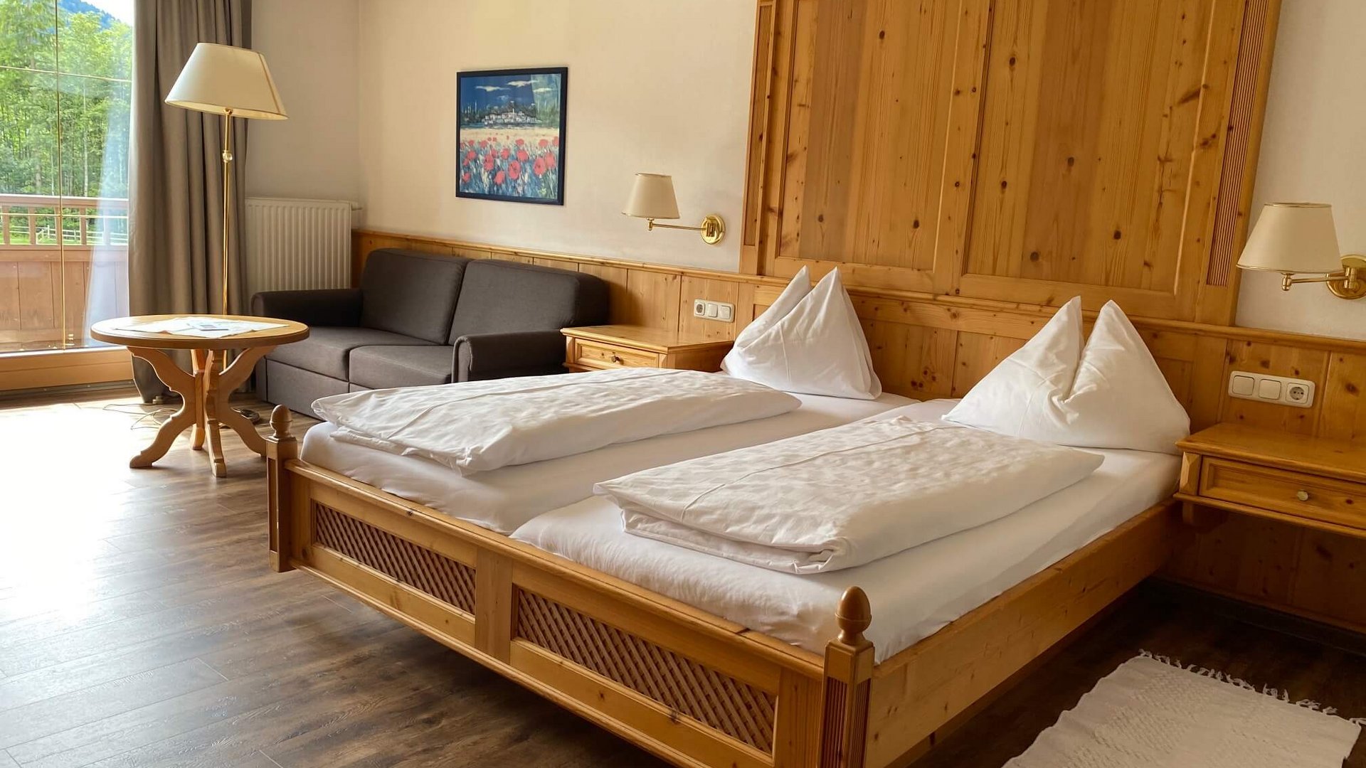 Cozy hotel room with double bed, sofa, and wooden furniture